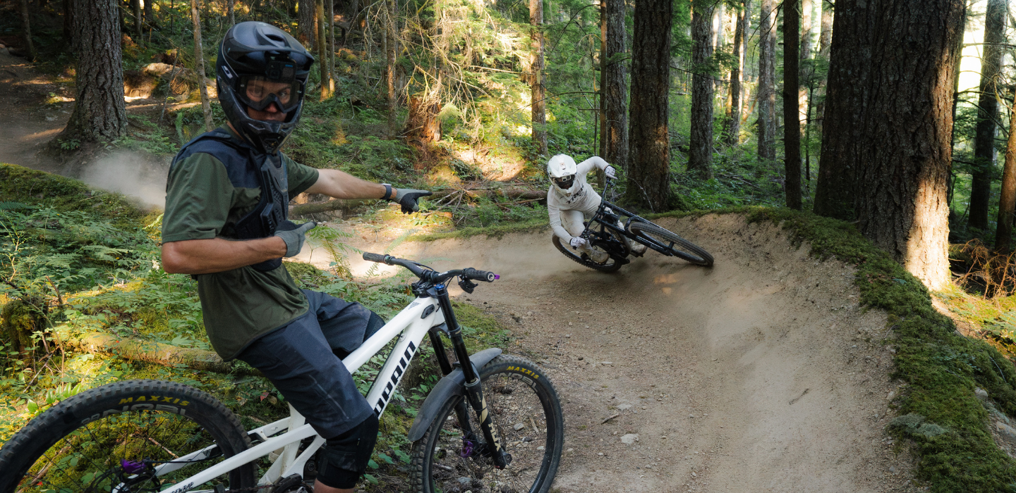 Two people riding bikes on a forest trail